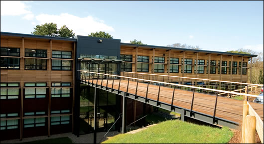 A commitment to conserving the environment in a broader sense was vital for the Orchard building, and two-thirds of the external cladding is cedar wood which blends well with the building's setting. Located in an eighteen acre woodland, the building's main entrance is across a footbridge