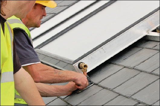 A flat plate solar collector being installed