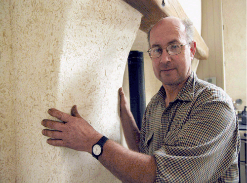 Robert Longwell, hemp farmer standing in his Hempire plastered traditional cottage